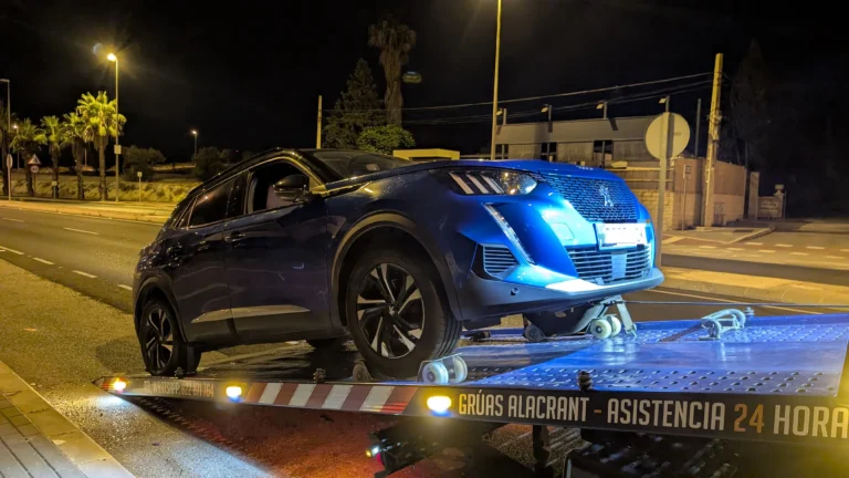 Coche azul transportado de noche en una grúa de plataforma