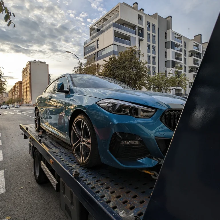 Turismo azul cargado en una grúa de plataforma junto a edificios